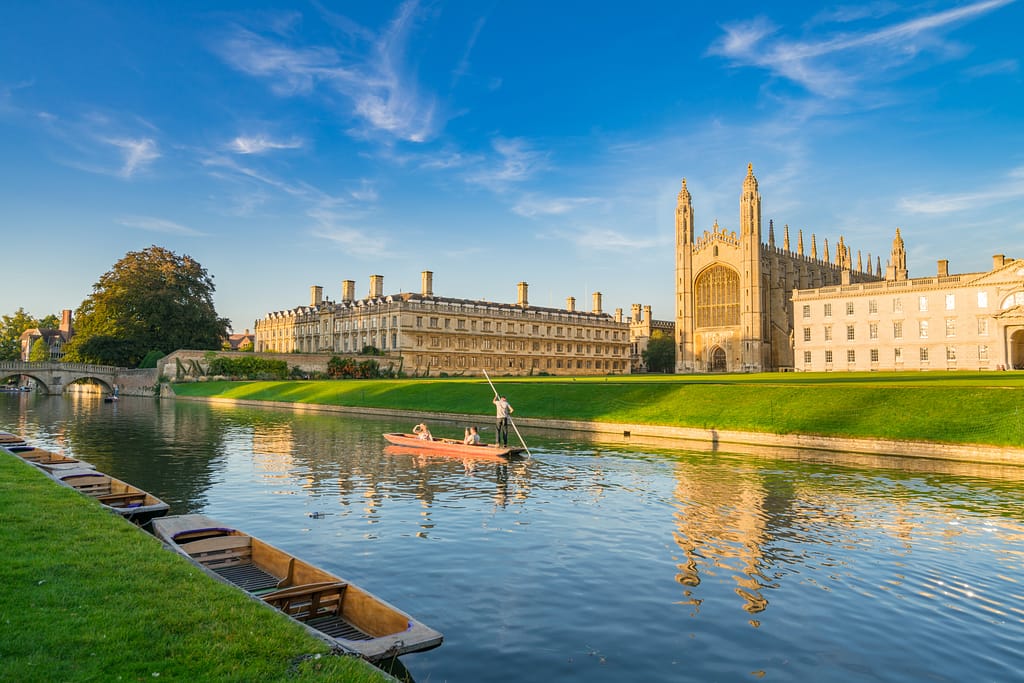 Beautiful view of college in Cambridge with people punting on ri